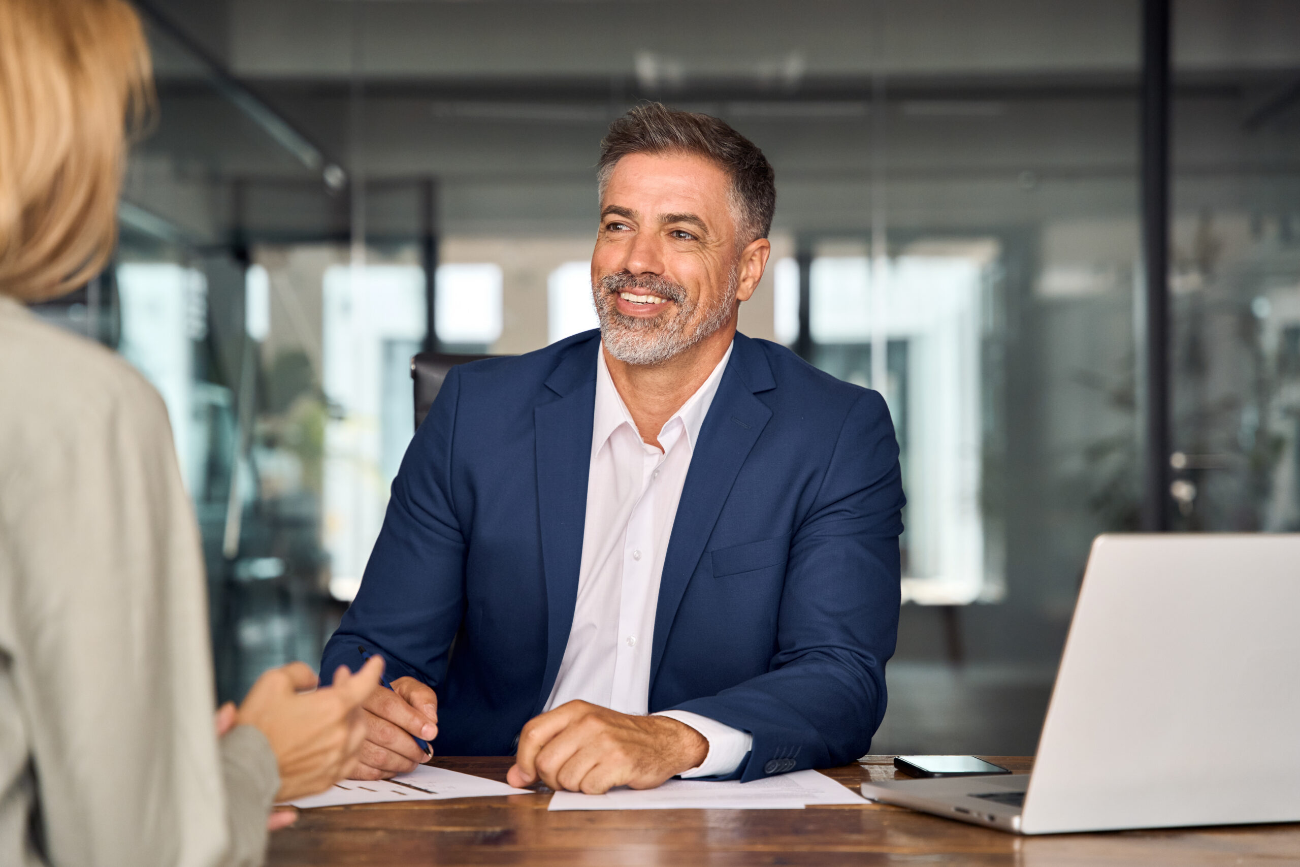 Lawyer or real estate agent make consultation for client for class action and PAGA claim. Mature Latin business man and European business woman discussing project on laptop sitting at table in office. Business people work together.