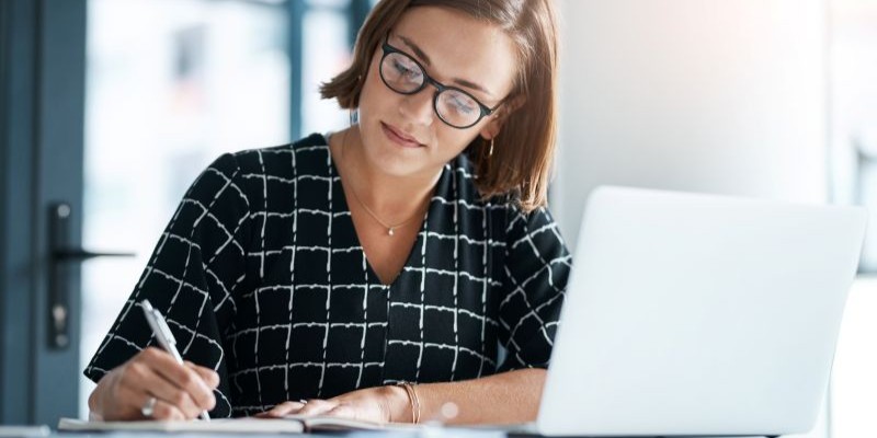 Woman writing notes next to a laptop to document evidence for a wrongful termination and retaliation claim