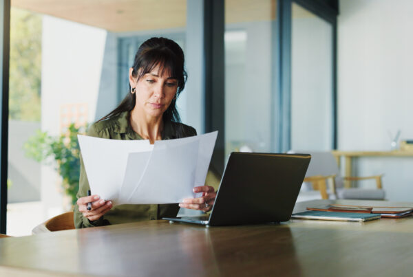 A California employee reviews a severance agreement at a home office table with a laptop open, considering whether to sign before the deadline.