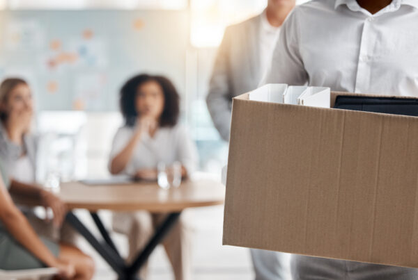 Employee carrying a box of belongings out of an office after being fired while on workers' comp in California