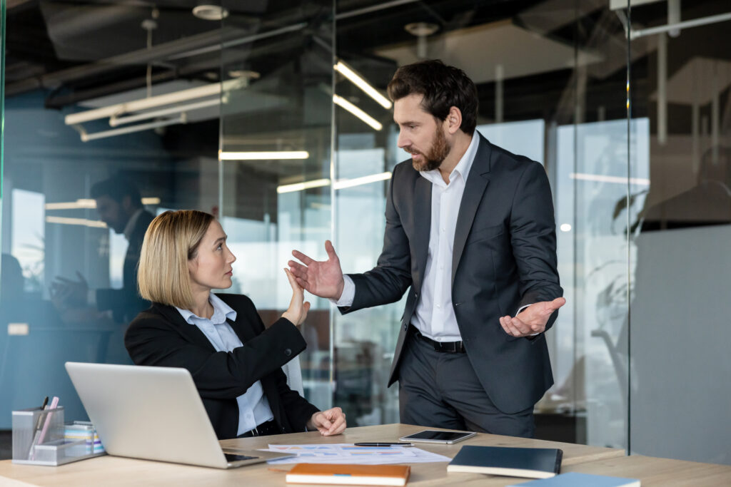 A manager confronting an employee at her desk in a corporate office, representing a workplace dispute that may constitute wrongful termination in California.