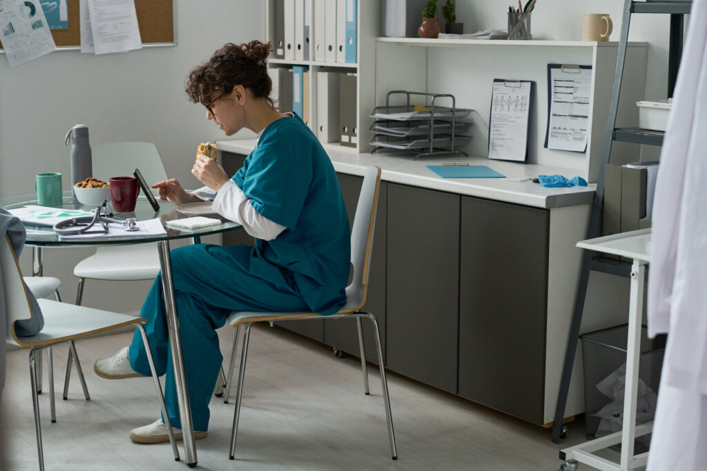 Healthcare worker in scrubs reviewing documents at a medical office desk, California minimum wage 2027 healthcare sector rates