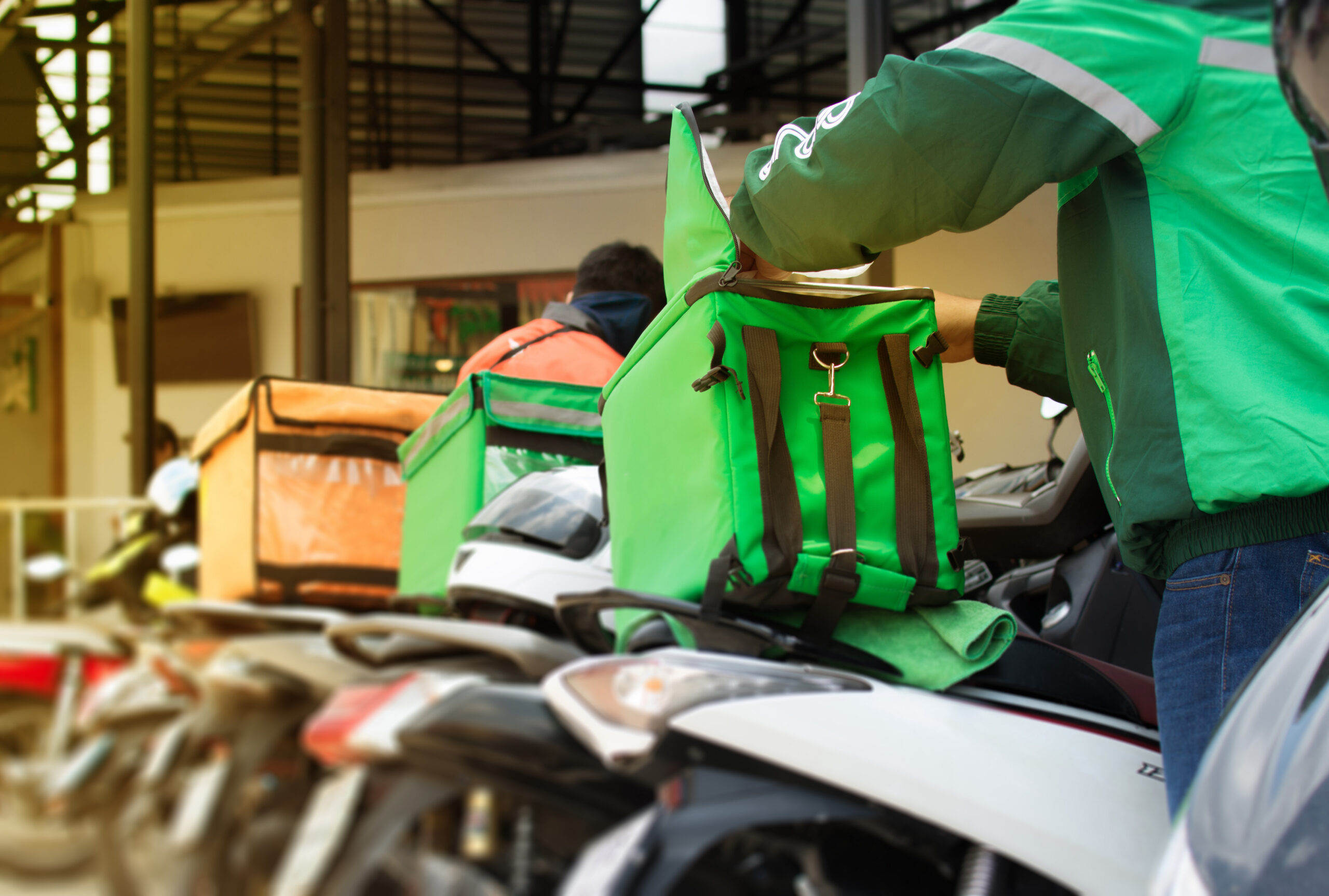 Food delivery drivers on motorcycles with thermal bags preparing for deliveries, representing gig economy workers who may qualify as employees under California's ABC test