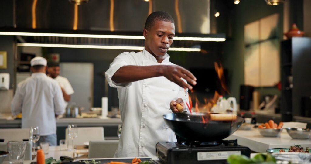 Restaurant cook working at the stove in a commercial kitchen, representing back-of-house employees and their tip pool eligibility under California law