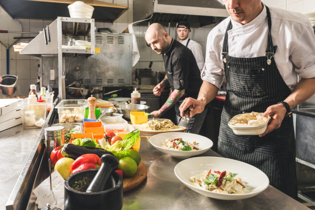 Restaurant kitchen workers plating dishes during service, representing food service employees in an industry with some of California's highest rates of wage violations and misclassification