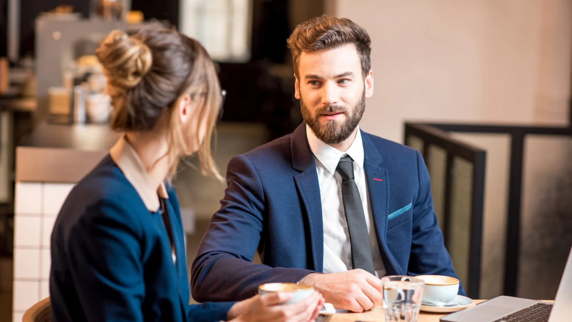 Two employees in business attire talking over coffee about their rights after a mass layoff in California
