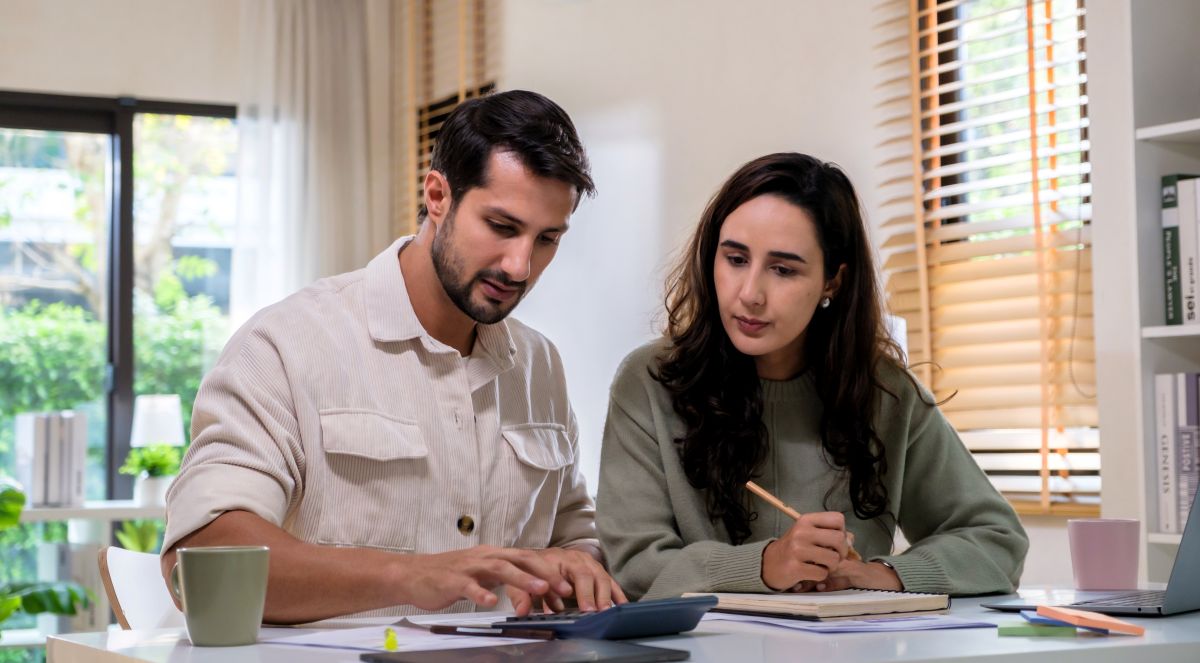 Two California employees reviewing pay stubs and calculating wages to verify minimum wage compliance in 2027