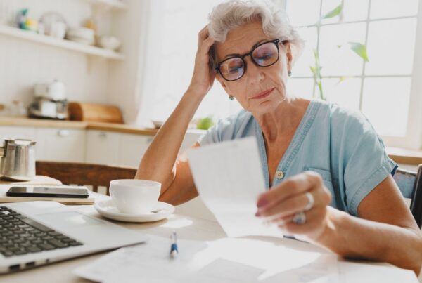 An older California employee reviews paperwork at home with a concerned expression, questioning whether her final paycheck was paid correctly