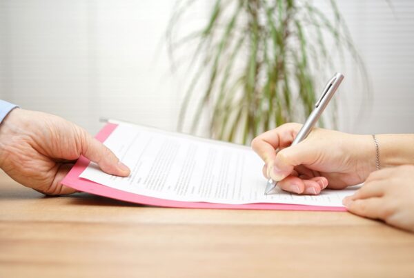 Employee signing a California severance pay agreement while an employer representative presents the document at a desk