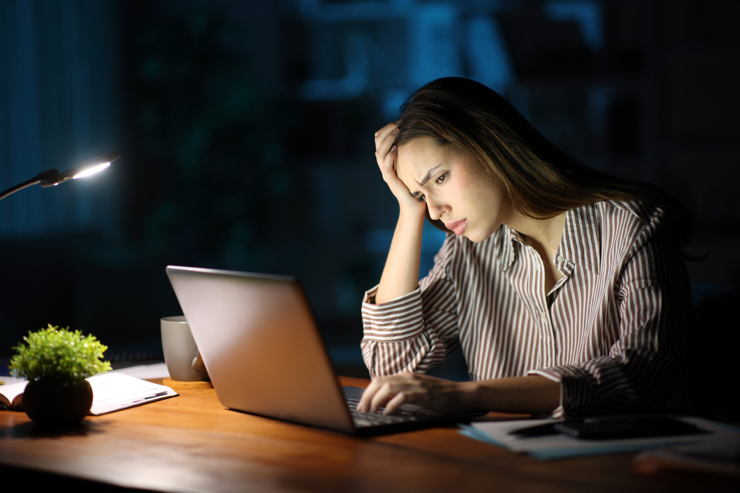 Employee reviewing her paycheck late at night, concerned about a wage discrepancy
