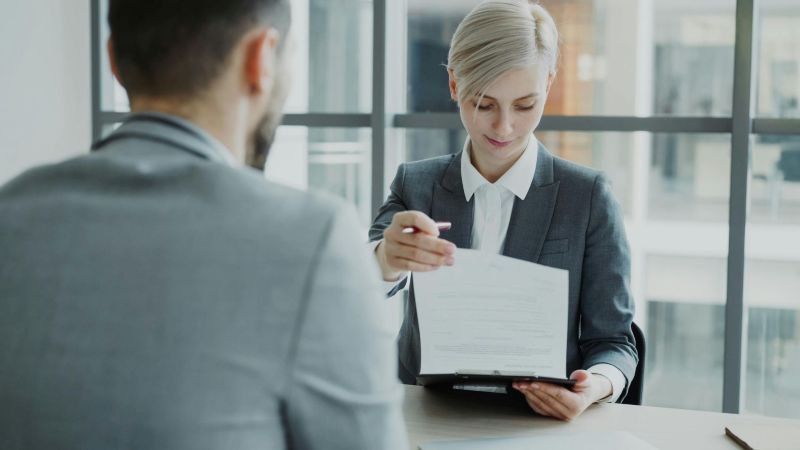 An attorney reviews employment documents with a client across a desk during a consultation meeting