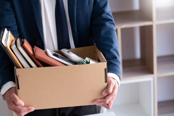 Employee carrying personal belongings in a box after being terminated from a job in California