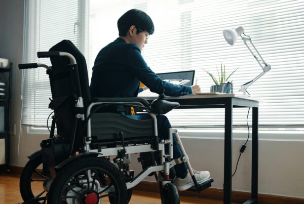 Employee using a wheelchair working at a home office desk while on disability leave in California
