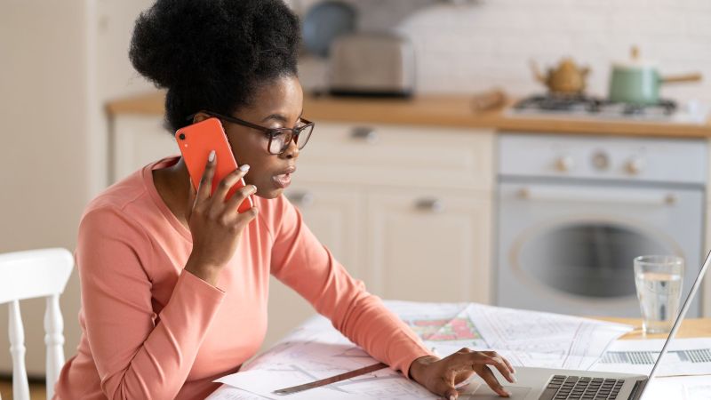 California employee at home on the phone with documents on the table, taking action after a wrongful termination based on an implied employment contract