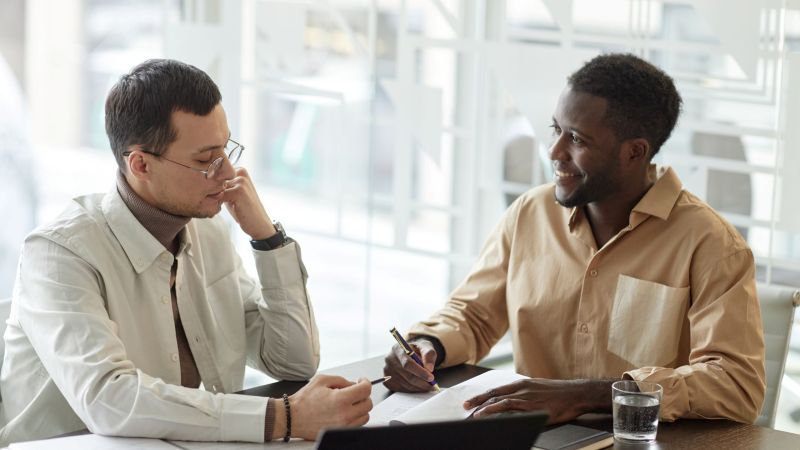Two men sit across from each other reviewing documents during a free Tameny claim case evaluation in California