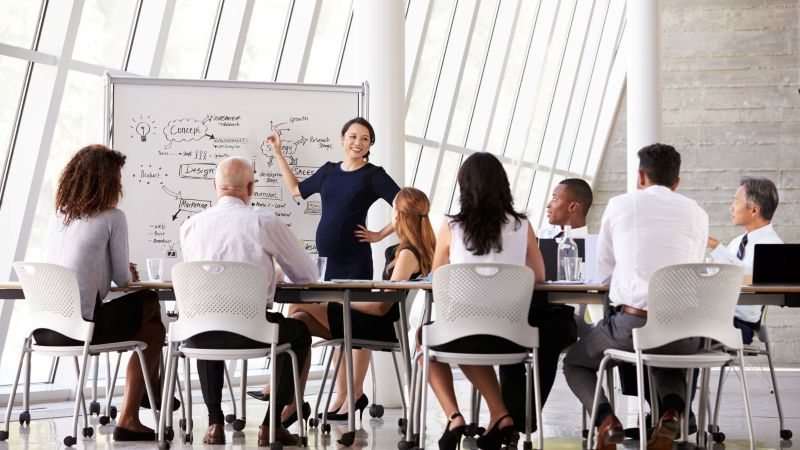 Visibly pregnant professional leading a team meeting, representing pregnancy as a protected class under FEHA California and the right to continue working without discrimination