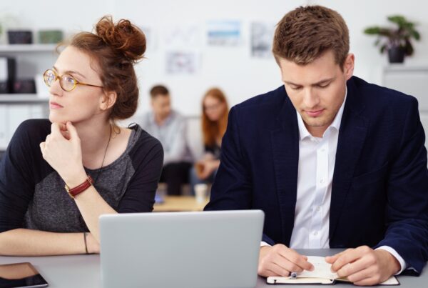 Employee experiencing a hostile work environment — excluded by a coworker at her desk while others meet nearby