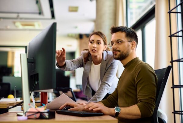 Manager leaning over employee's shoulder at computer in a hostile work environment