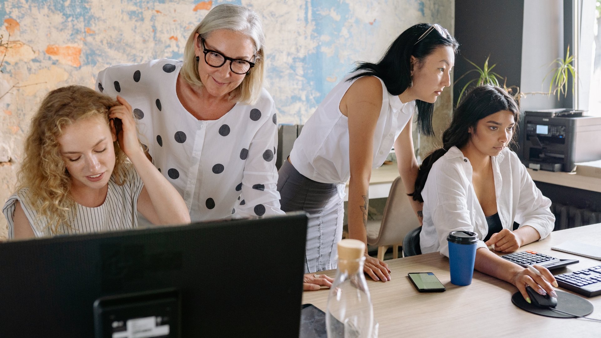 Manager supervising office employees at computers, illustrating the duties test for exempt vs non exempt employee classification in California