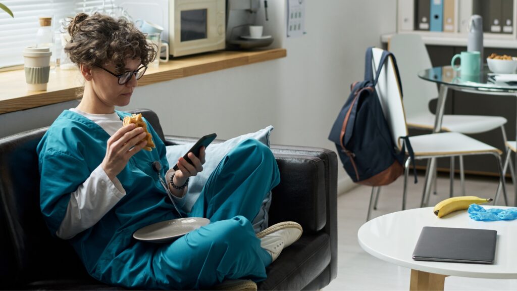 Nurse on break in a hospital break room checking their phone — healthcare workers on extended California shifts are entitled to double time pay after 12 hours in a single workday