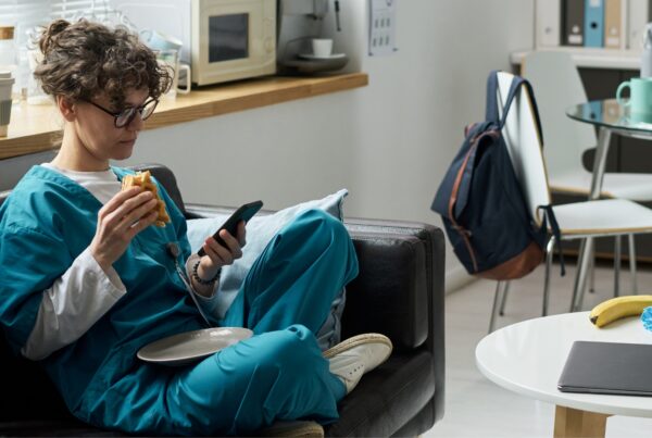 Nurse on break in a hospital break room checking their phone — healthcare workers on extended California shifts are entitled to double time pay after 12 hours in a single workday