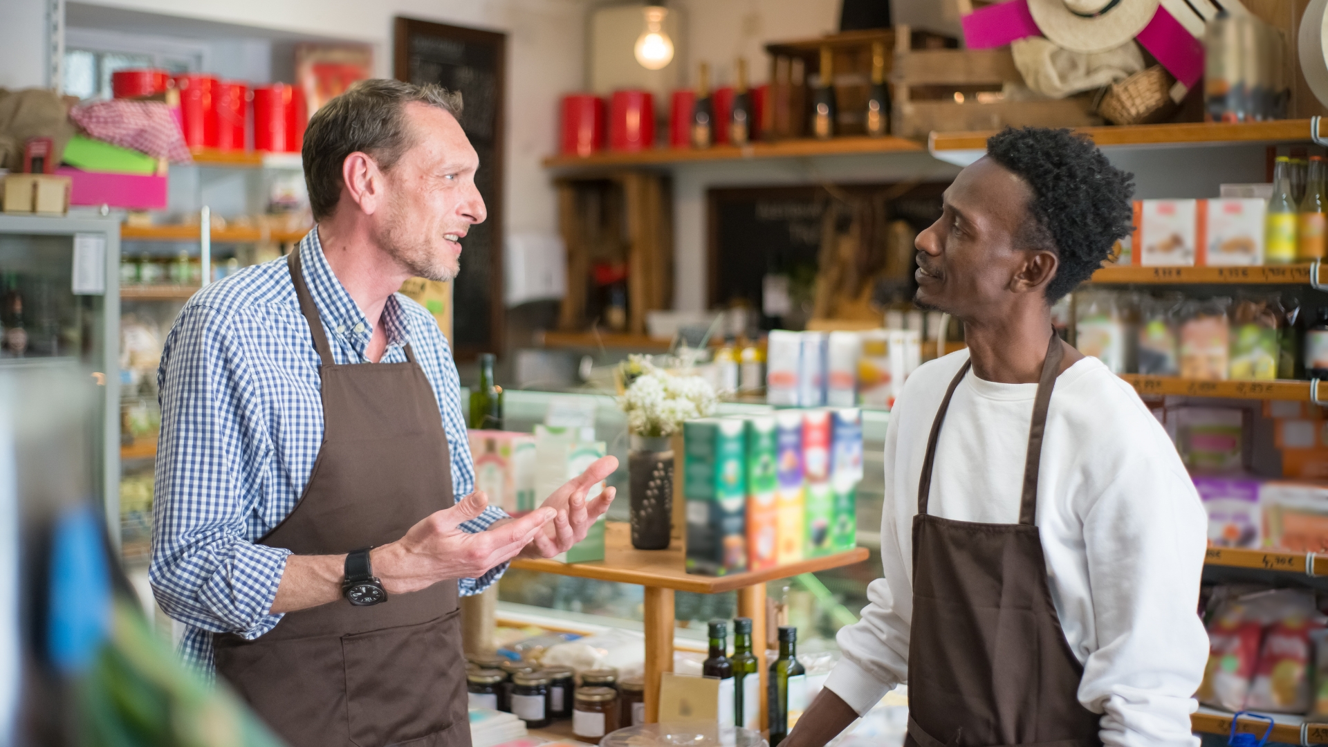 Two retail workers in matching aprons talking in a California store, a common setting for exempt vs non exempt employee misclassification