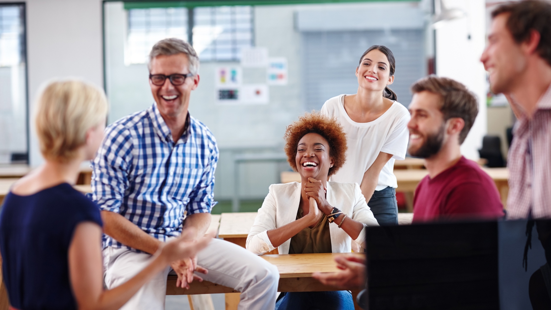 Diverse group of California coworkers laughing together, representing the employees an employer must treat fairly under FEHA