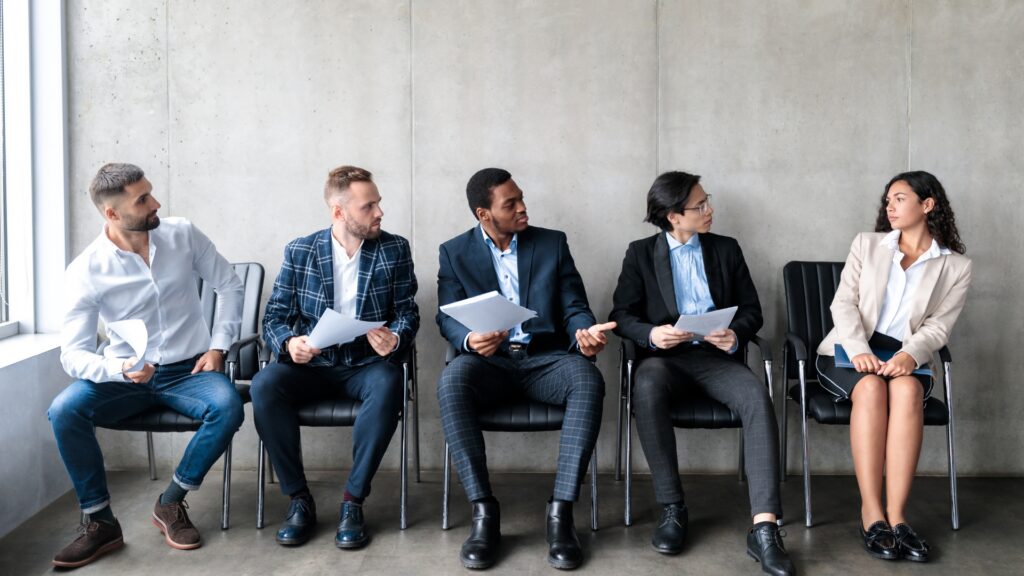 Female employee seated apart from a row of male candidates, illustrating gender discrimination in a California hiring process