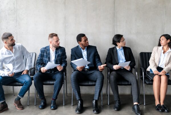 Female employee seated apart from a row of male candidates, illustrating gender discrimination in a California hiring process