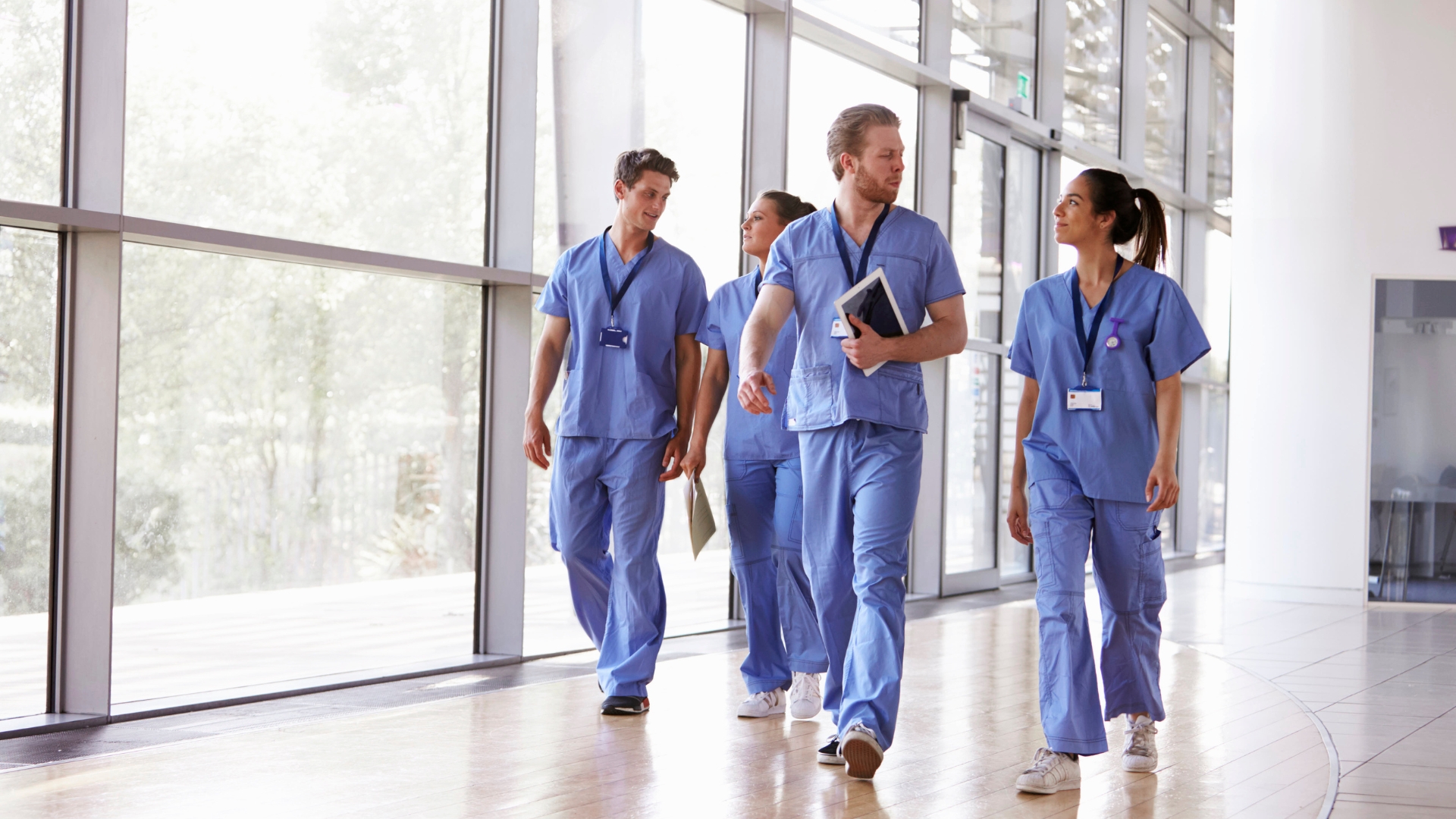 Health care employees in scrubs walking together through a hospital hallway in San Bernardino