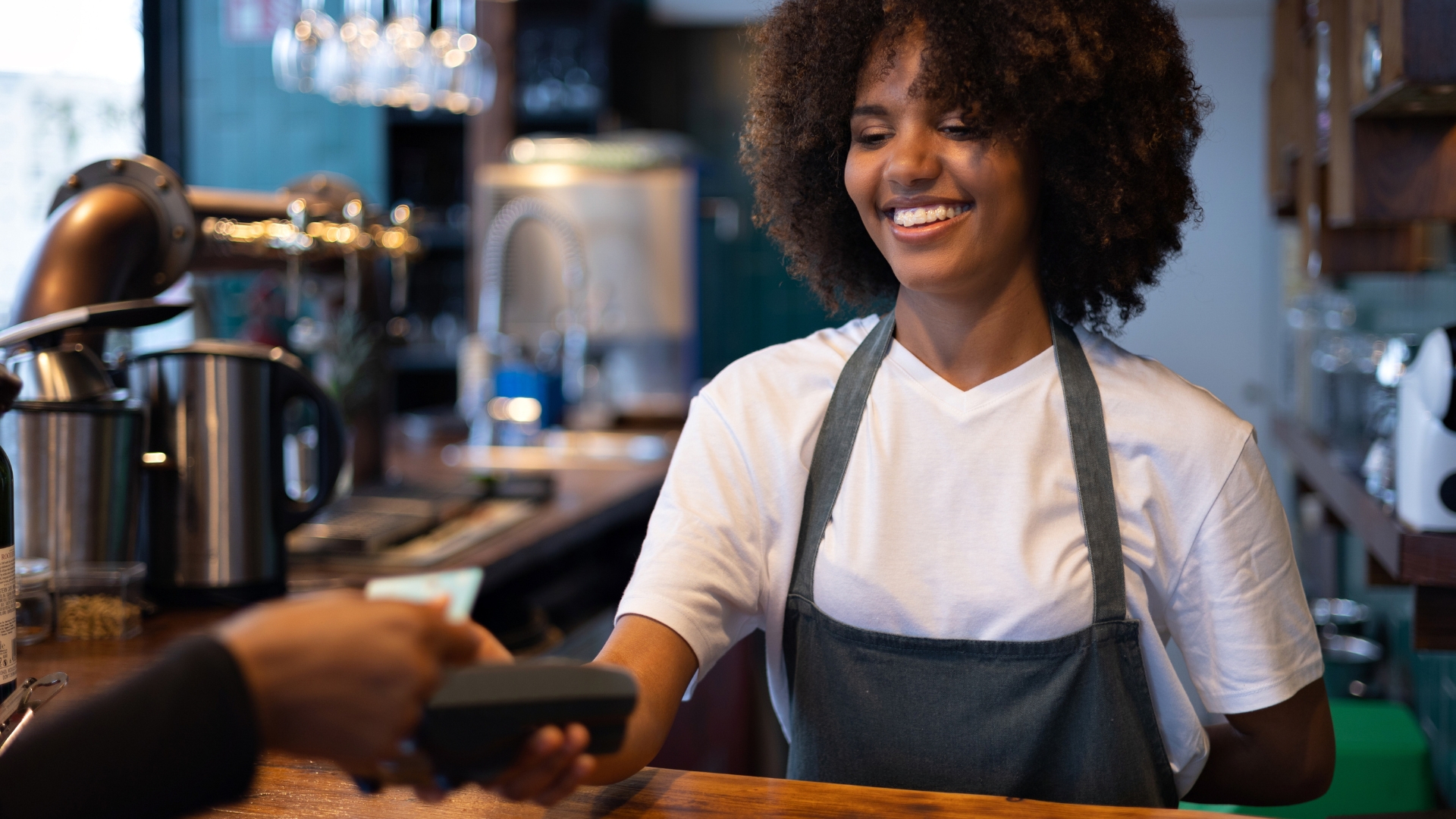 Barista processing a card payment at a coffee shop, an hourly employee covered by new California labor laws