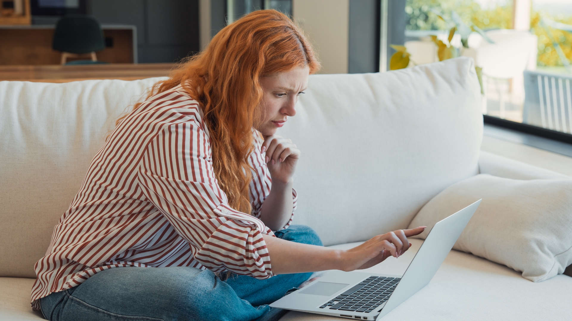 Woman looking concerned while checking a job rejection email on her laptop at home