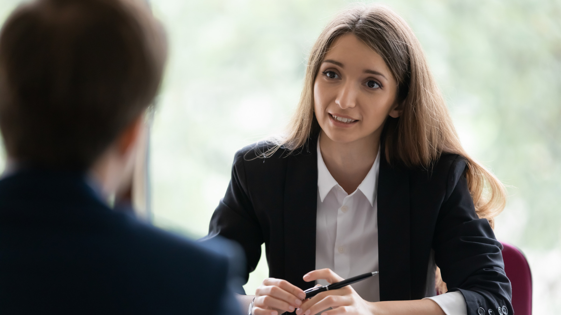 San Francisco employee in a tense meeting with her manager, holding a pen at the table.