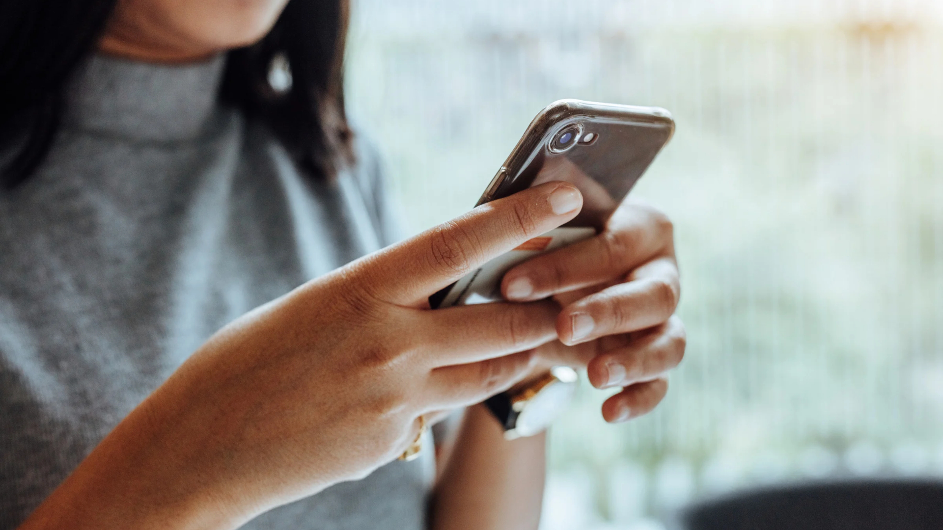 Close-up of hands reviewing a text message on a phone, evidence when documenting quid pro quo harassment