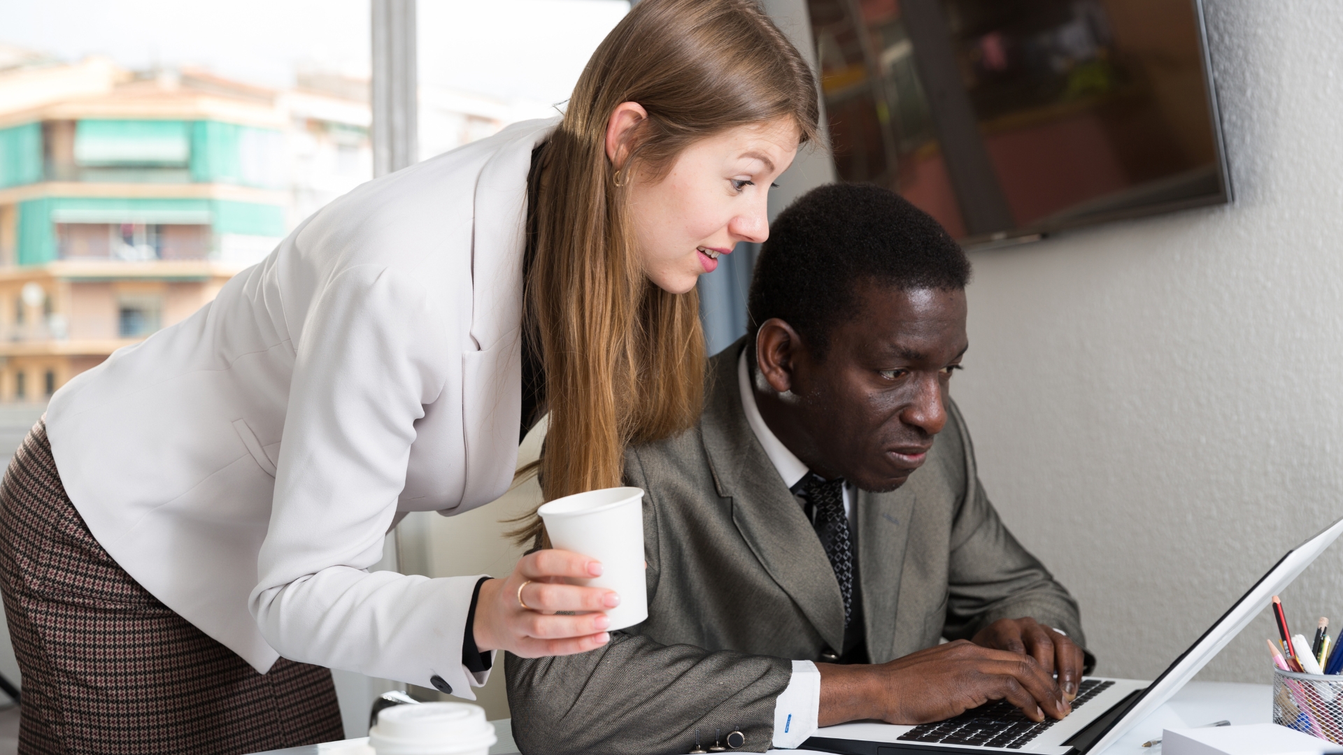 Coworker leaning in too close at a colleague's desk, a common sign of sexual harassment at work