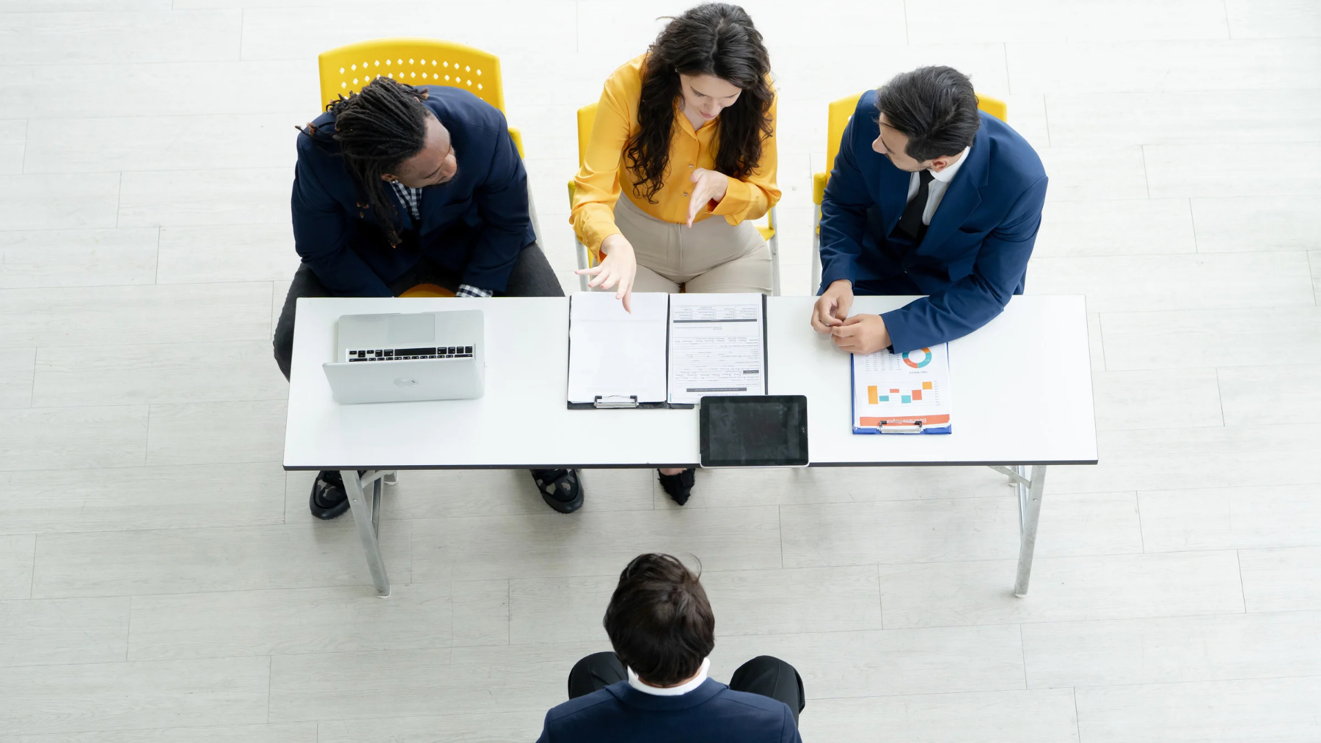 Overhead view of a three-person hiring panel reviewing an applicant's forms during a job interview.