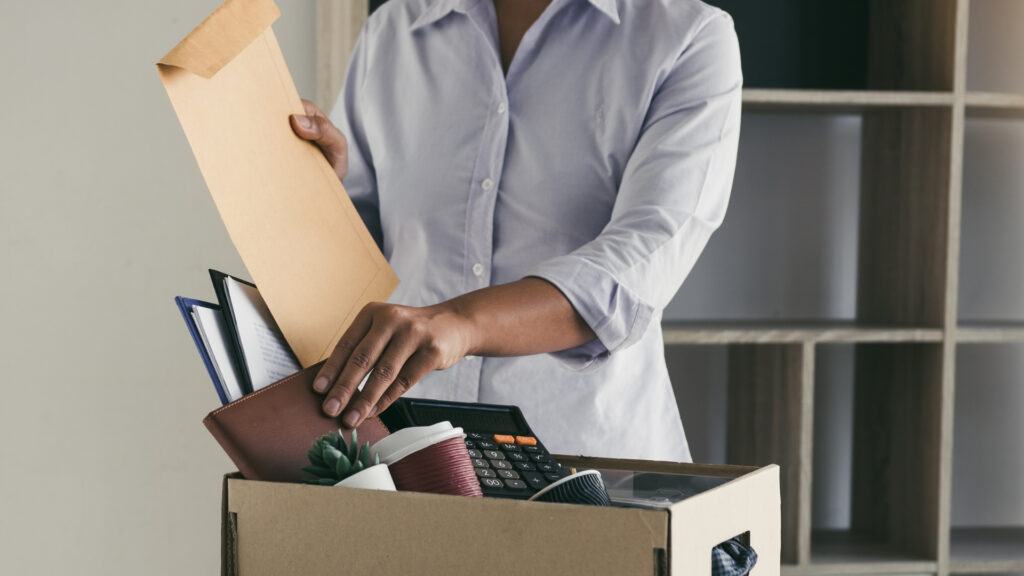 An employee packs personal desk items into a box after being let go in an AI layoff.