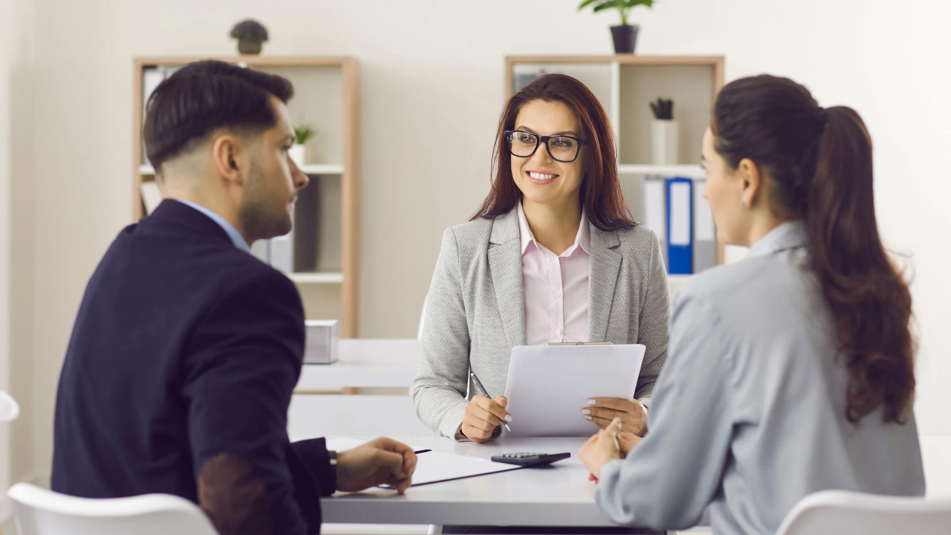Attorney smiling while reviewing paperwork with two clients during a consultation meeting