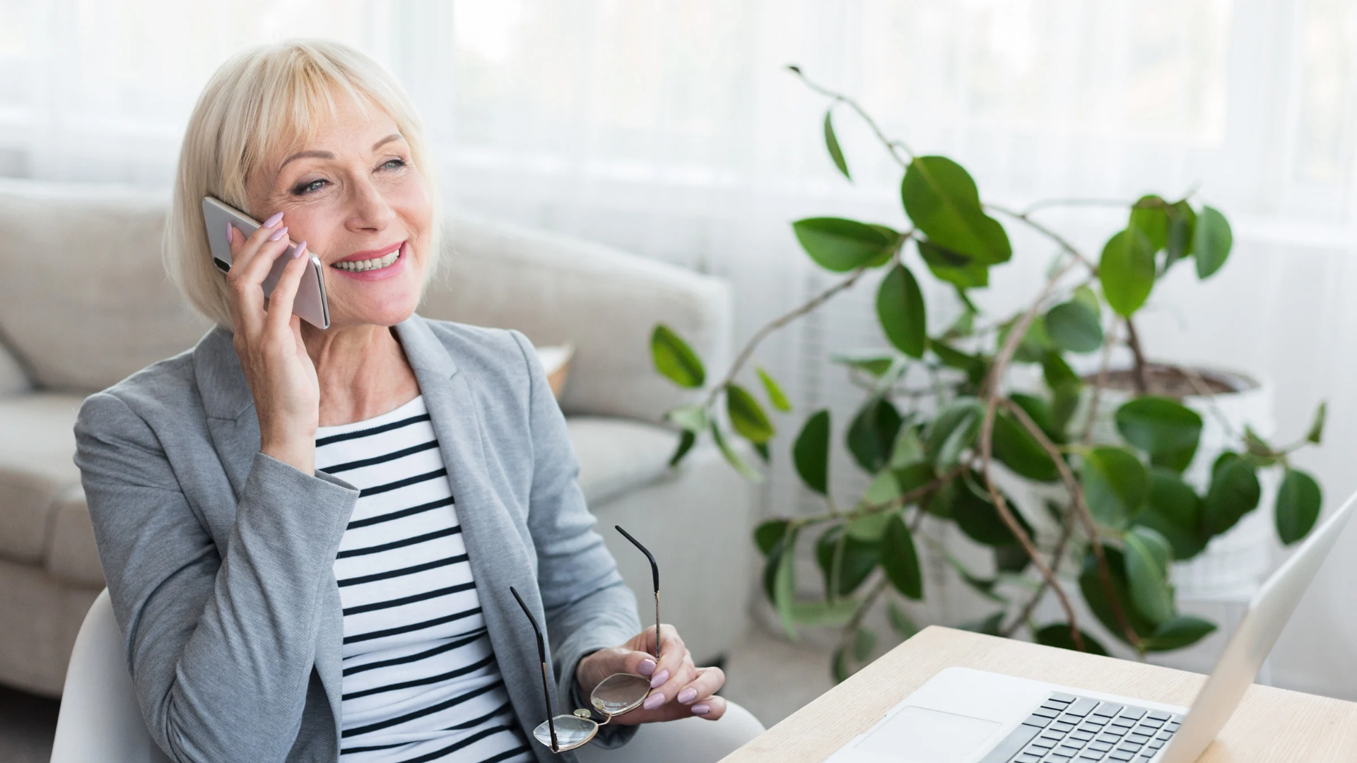 Smiling woman in her sixties on a phone call at a sunlit desk about her severance agreement over 40