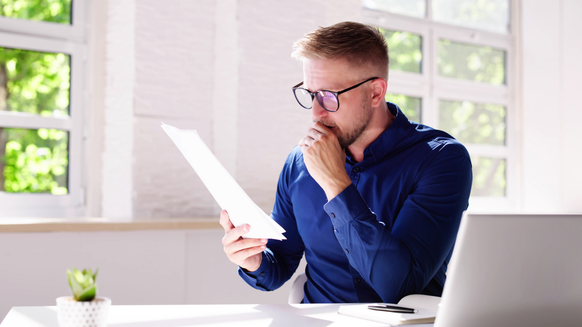 Employee reviewing a printed document closely before deciding whether to sign it