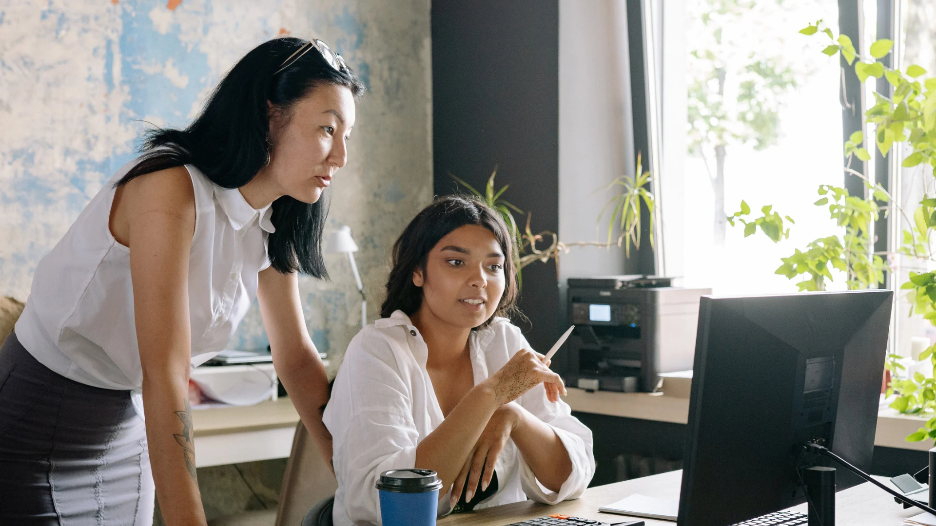 Two salaried office employees reviewing work on a monitor, roles an Orange County wage and hour lawyer checks for overtime
