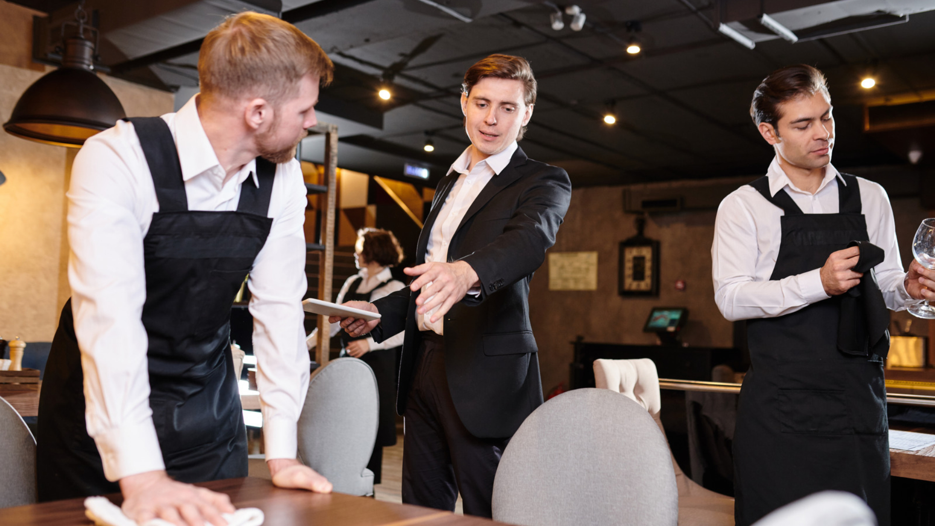 A restaurant manager directs employees who are working off the clock to finish closing tasks.