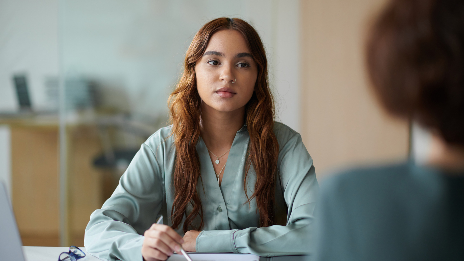 Employee sitting across from her manager during a tense conversation, a quid pro quo harassment scenario