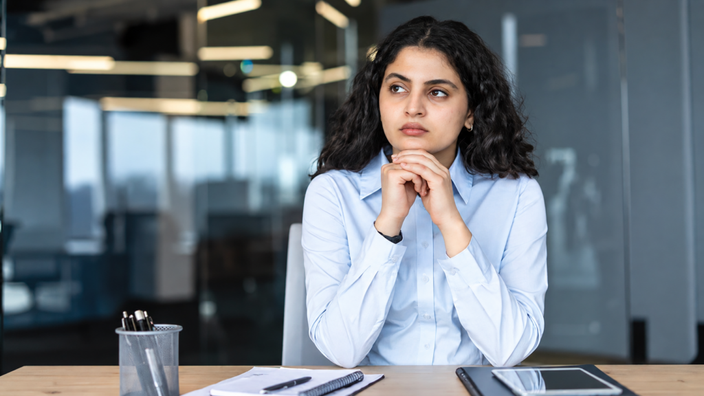 Employee pausing to think at her desk, weighing whether a workplace situation is quid pro quo harassment