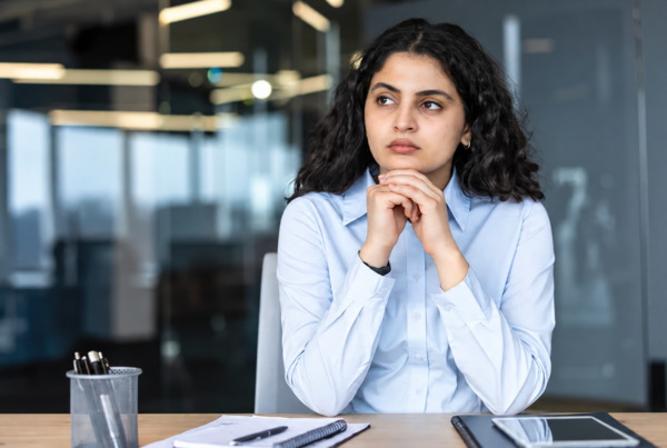 Employee pausing to think at her desk, weighing whether a workplace situation is quid pro quo harassment