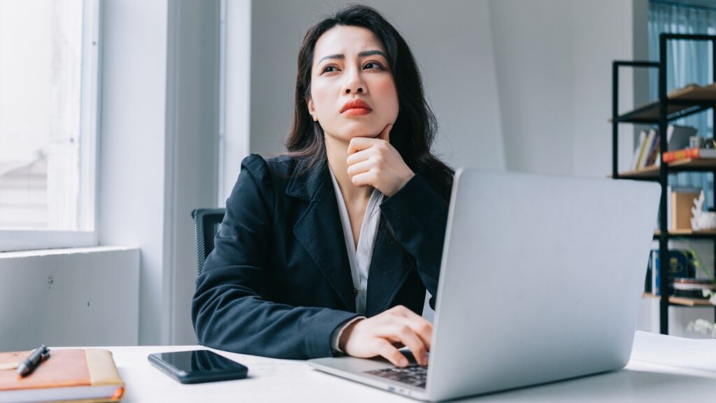 Woman sitting at her desk looking distressed after being sexually harassed at work