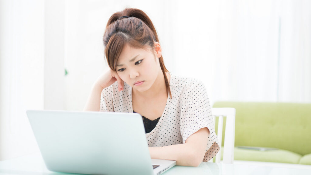 Employee sitting at a laptop, hesitant expression, weighing whether to report sexual harassment at work