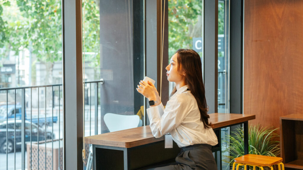 Employee with a work ID badge holding a coffee mug by a window during a paid rest break under the California 10-minute break law