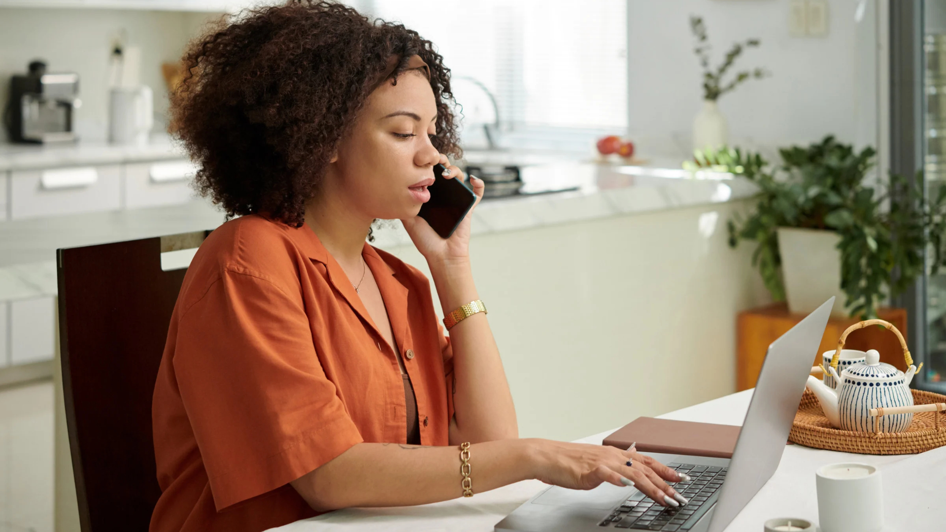 Employee talks with a Woodland Hills employment lawyer by phone from home while typing on her laptop