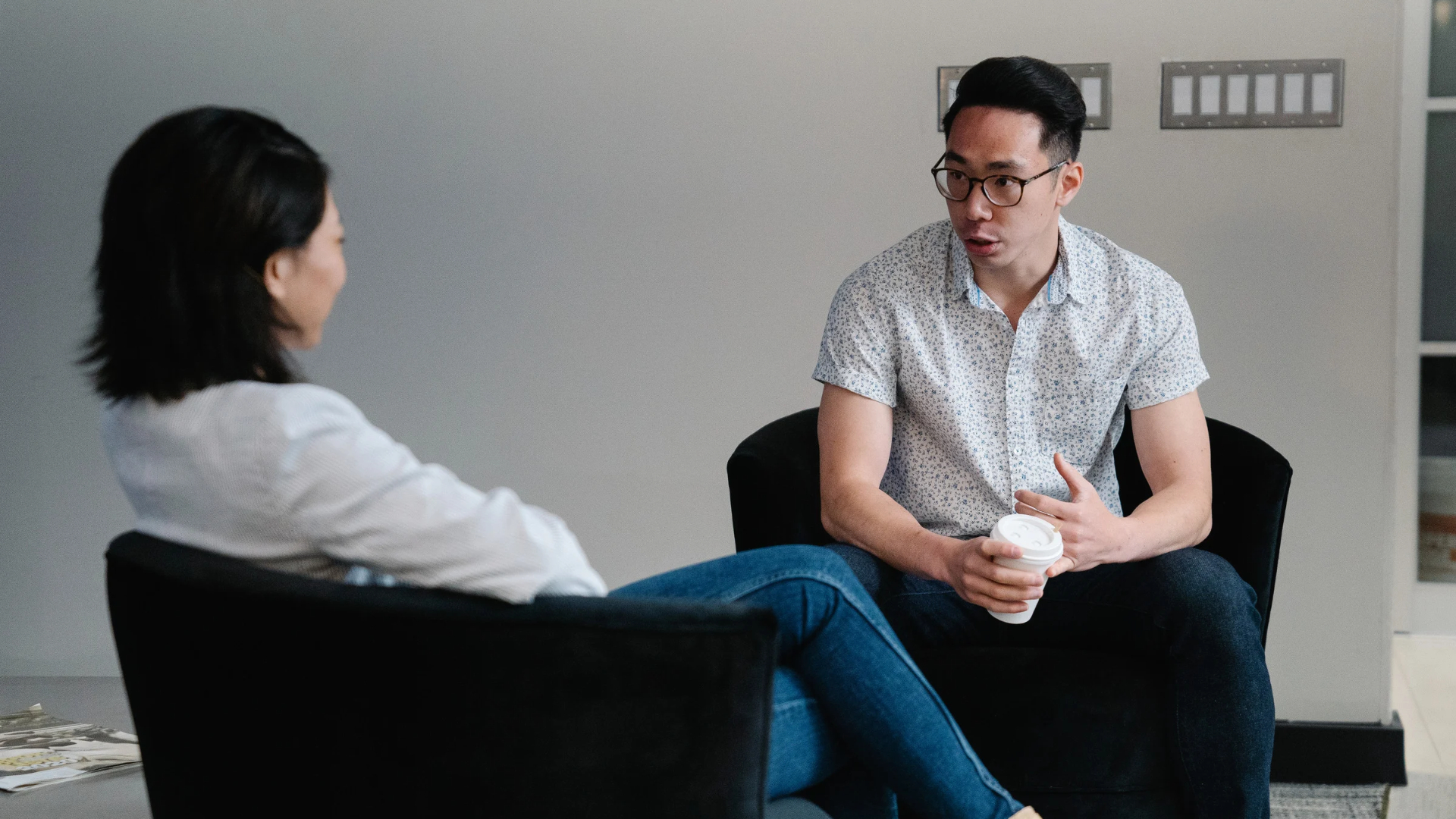 Employee holding a coffee cup explains a workplace discrimination concern during a private conversation